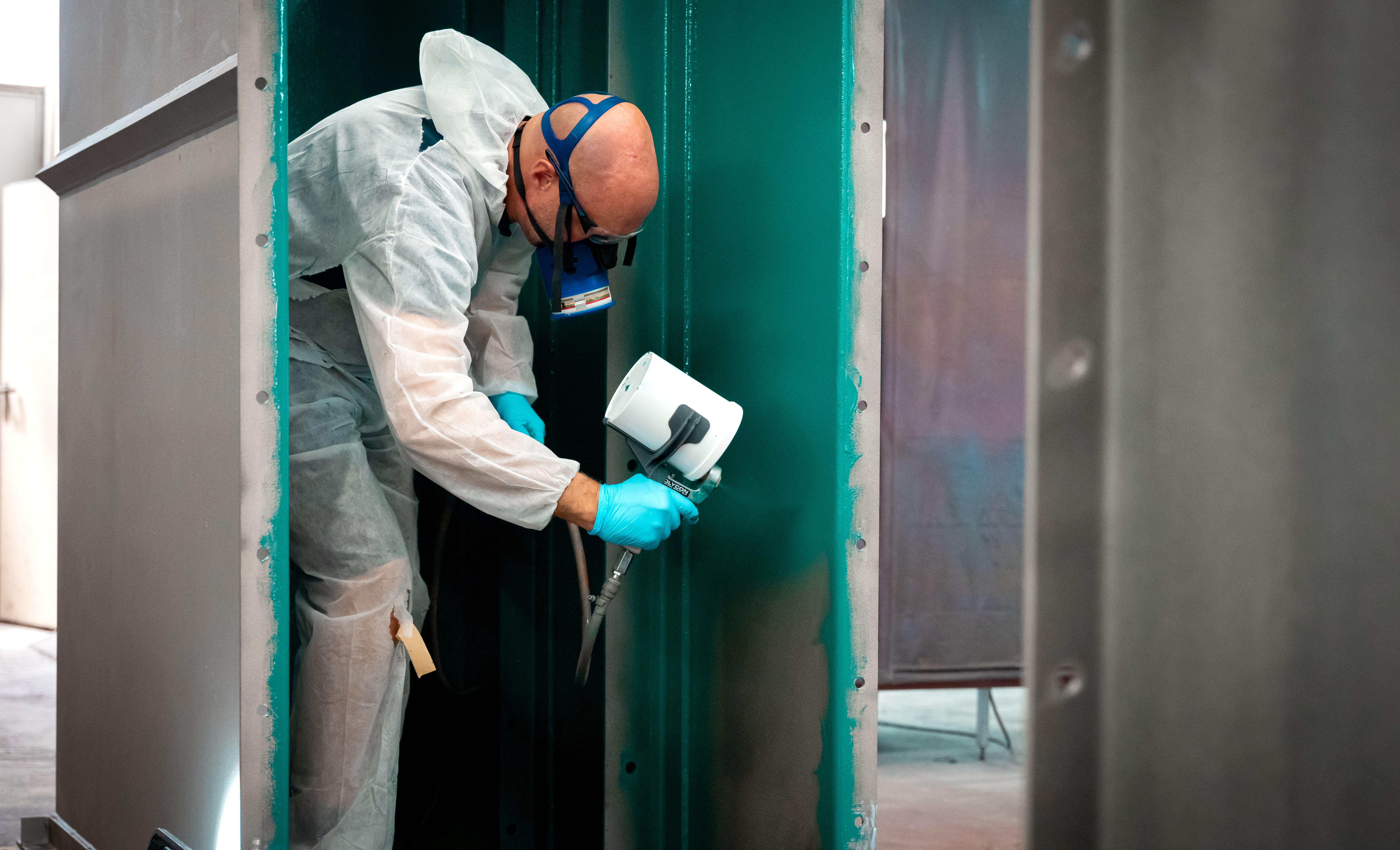 Muž v maske nastrieka zelenú kontrolnú vrstvu