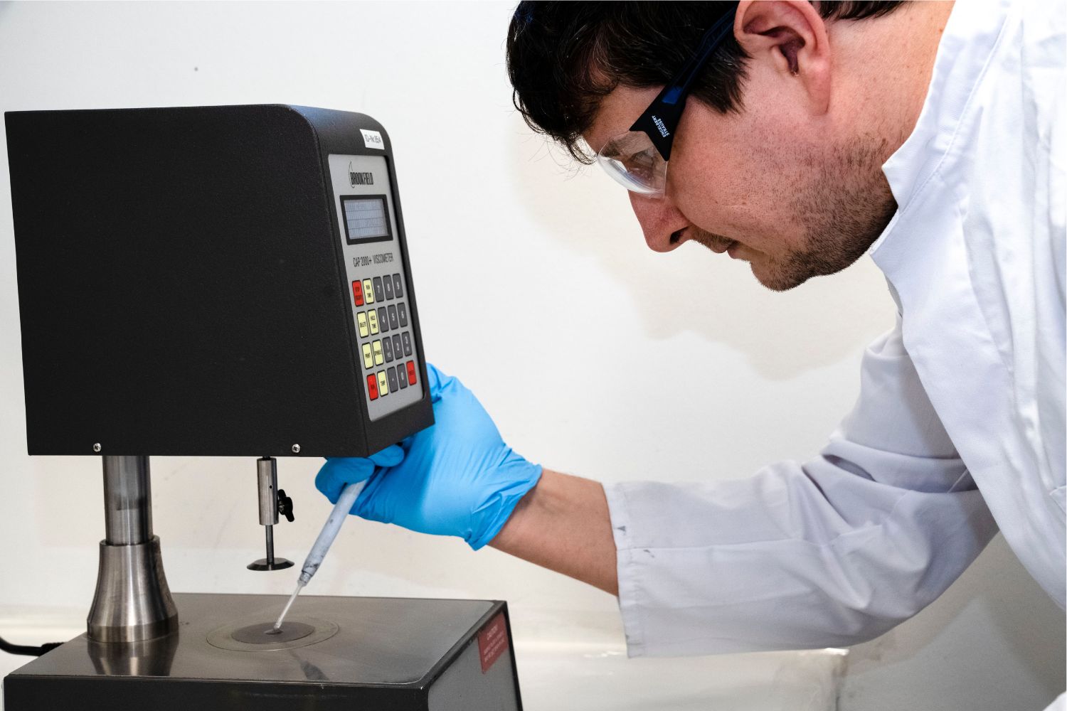 Muž v bielom plášti nanáša niečo z pipety na povrch